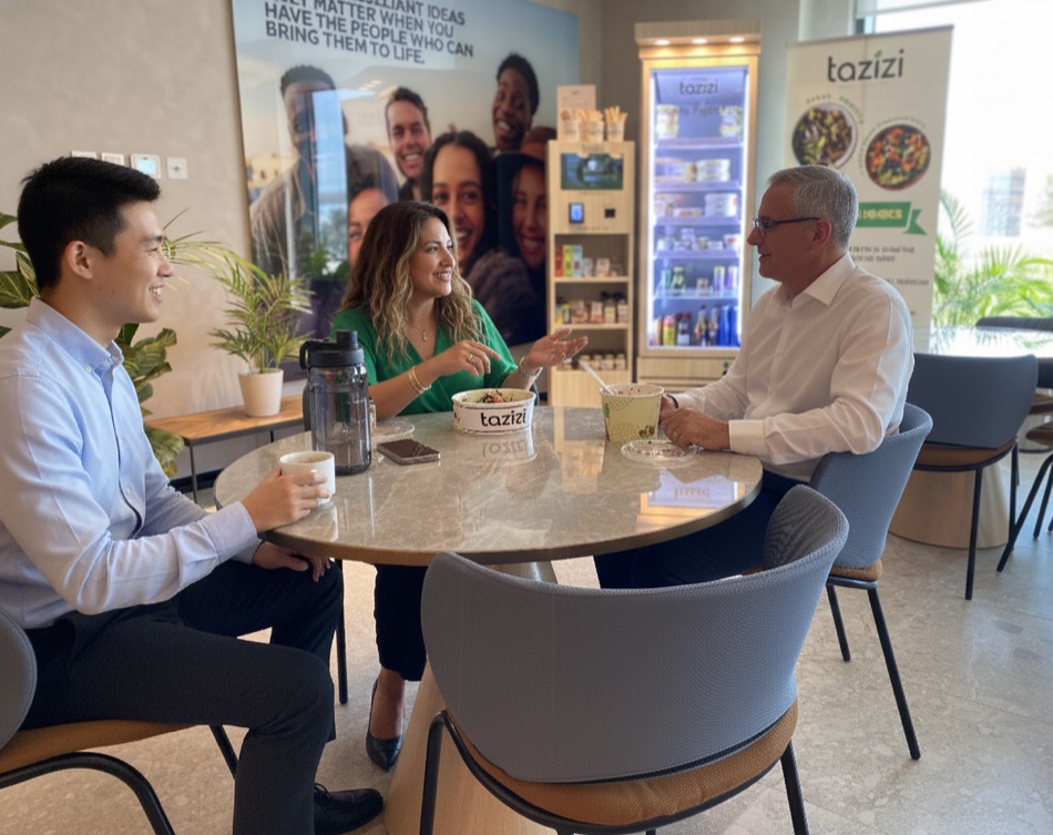Colleagues sharing Tazizi meals at a table in their office